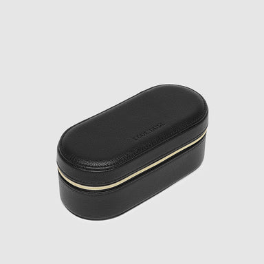 Black oval-shaped jewelry box with gold interior on a light gray background
