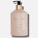 A pink glass bottle with a gold pump containing hand soap, labeled 'L'AVANT Collective', with a hint of shadow on the bottom right.